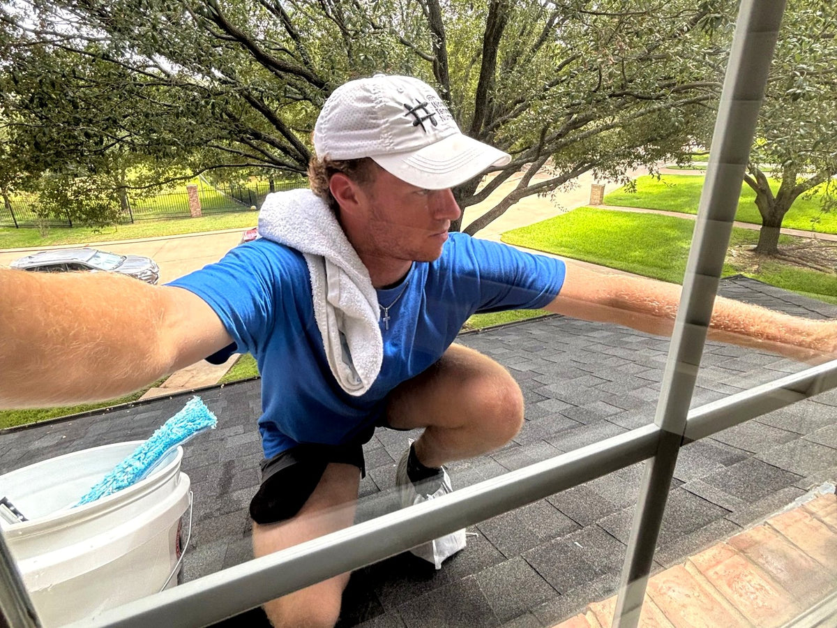 Clay, owner of Windows by Clay, cleaning an exterior window